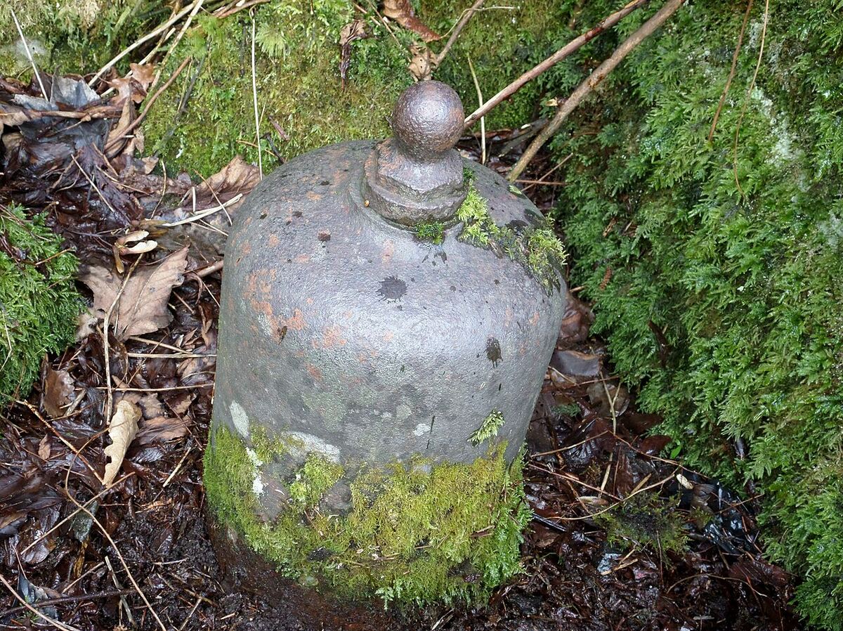An old cast-iron hydraulic ram pump covered in moss